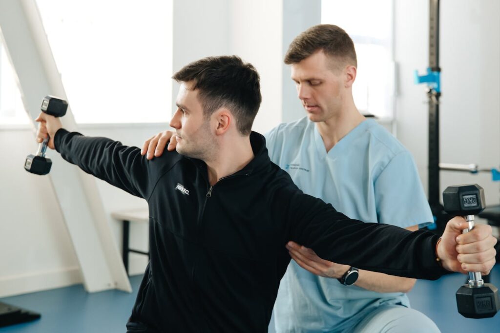 Man Supporting Patient who Lifting Dumbbells