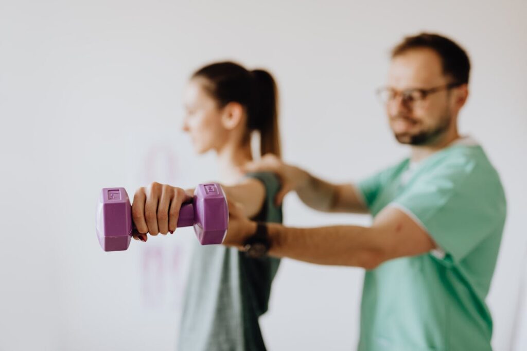 Chiropractor examining female patient with reached arm and dumbbell