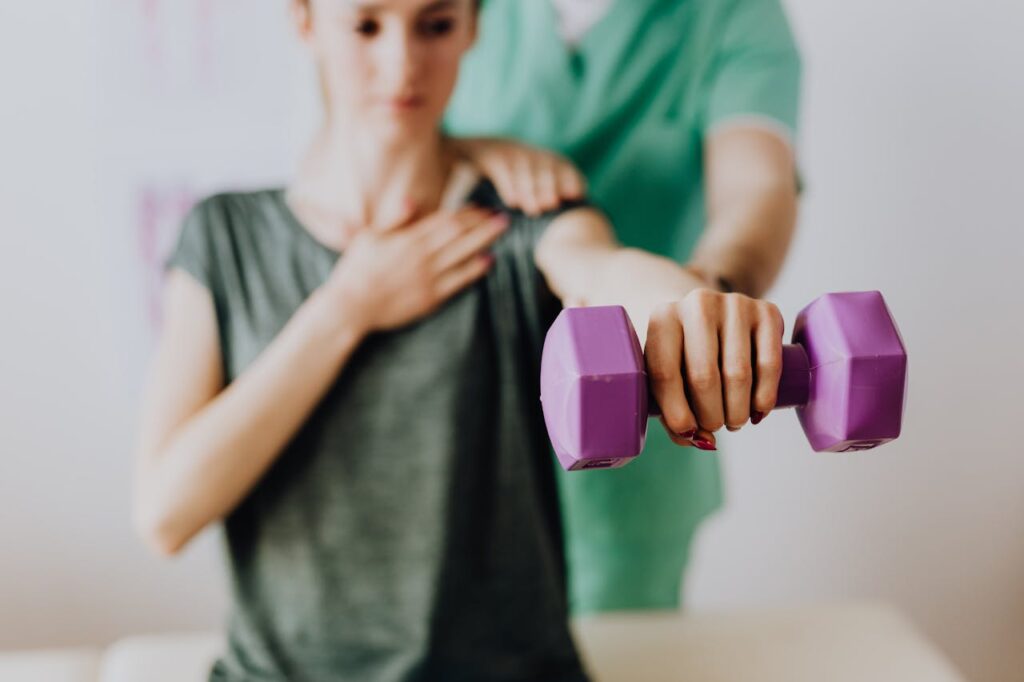 Osteopath assisting patient with dumbbell in hand